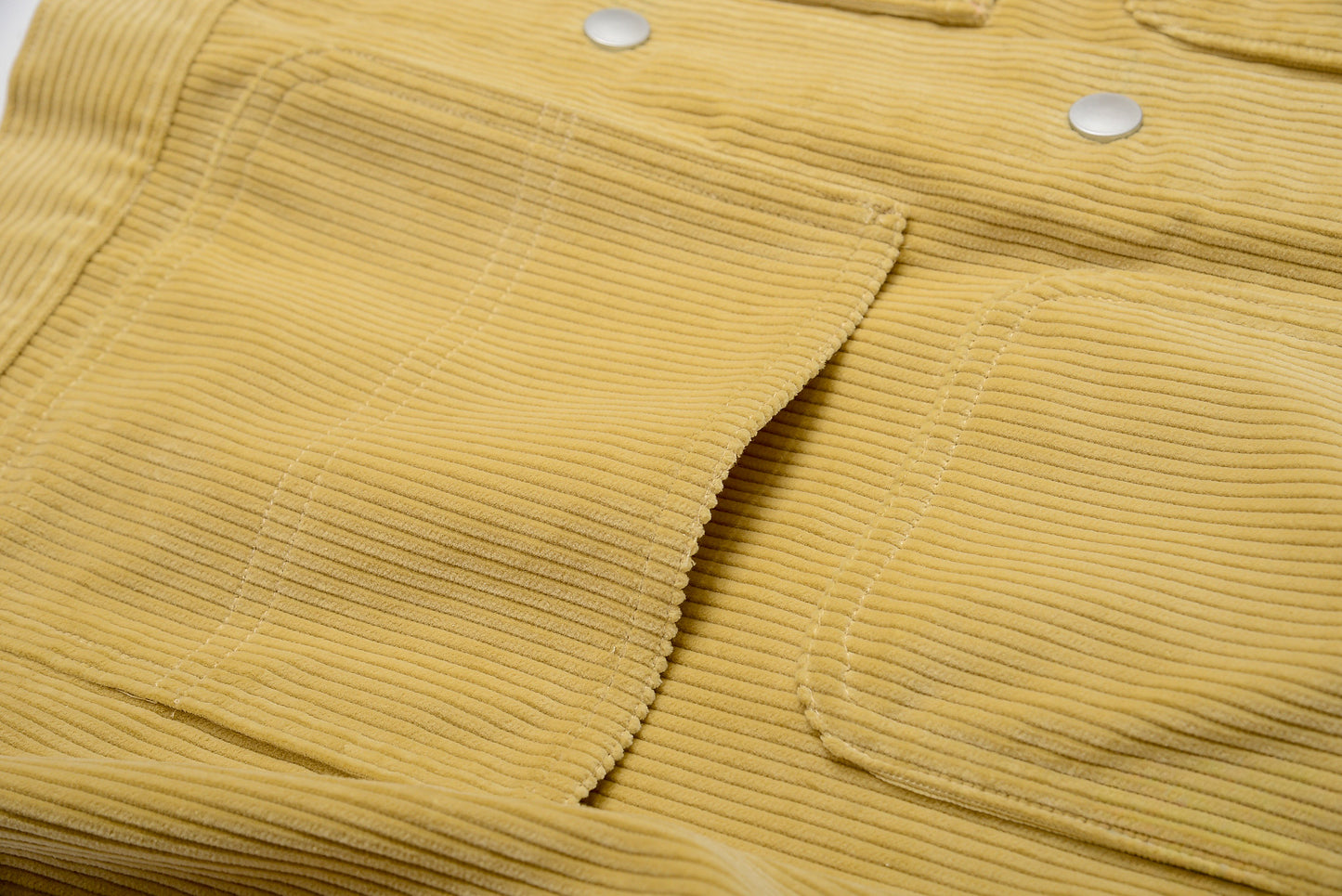 Close-up of a mustard yellow corduroy fabric with button details #color_creamy-yellow