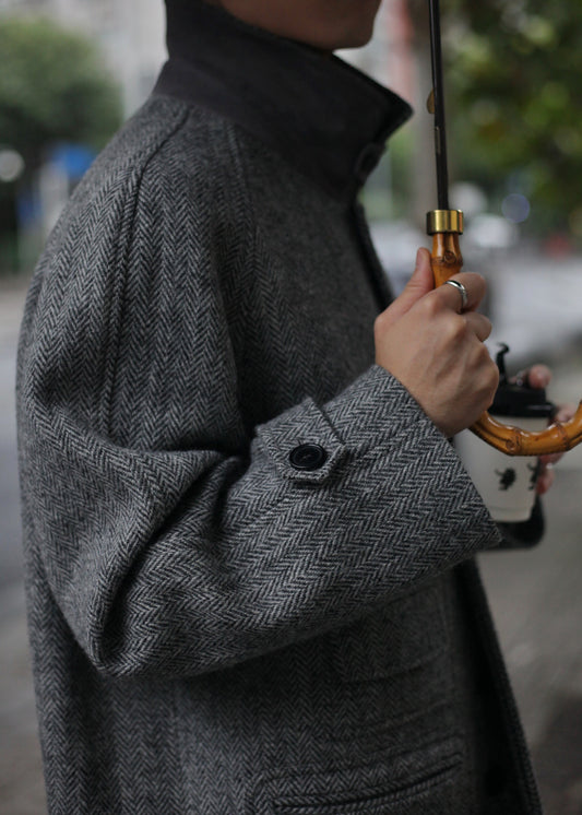 Close-up sleeve and pocket detail of Moonland's Balmacaan coat for men, made of Harris Tweed grey tone herringbone pattern. convertible collar with a durable sheepskin undercollar.