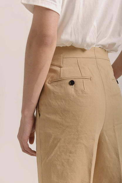 Close-up detail of  model wearing Moonland Ivy Chinos in beige Roger Laviale cotton twill, highlighting welt back pocket with button closure and fine stitching.