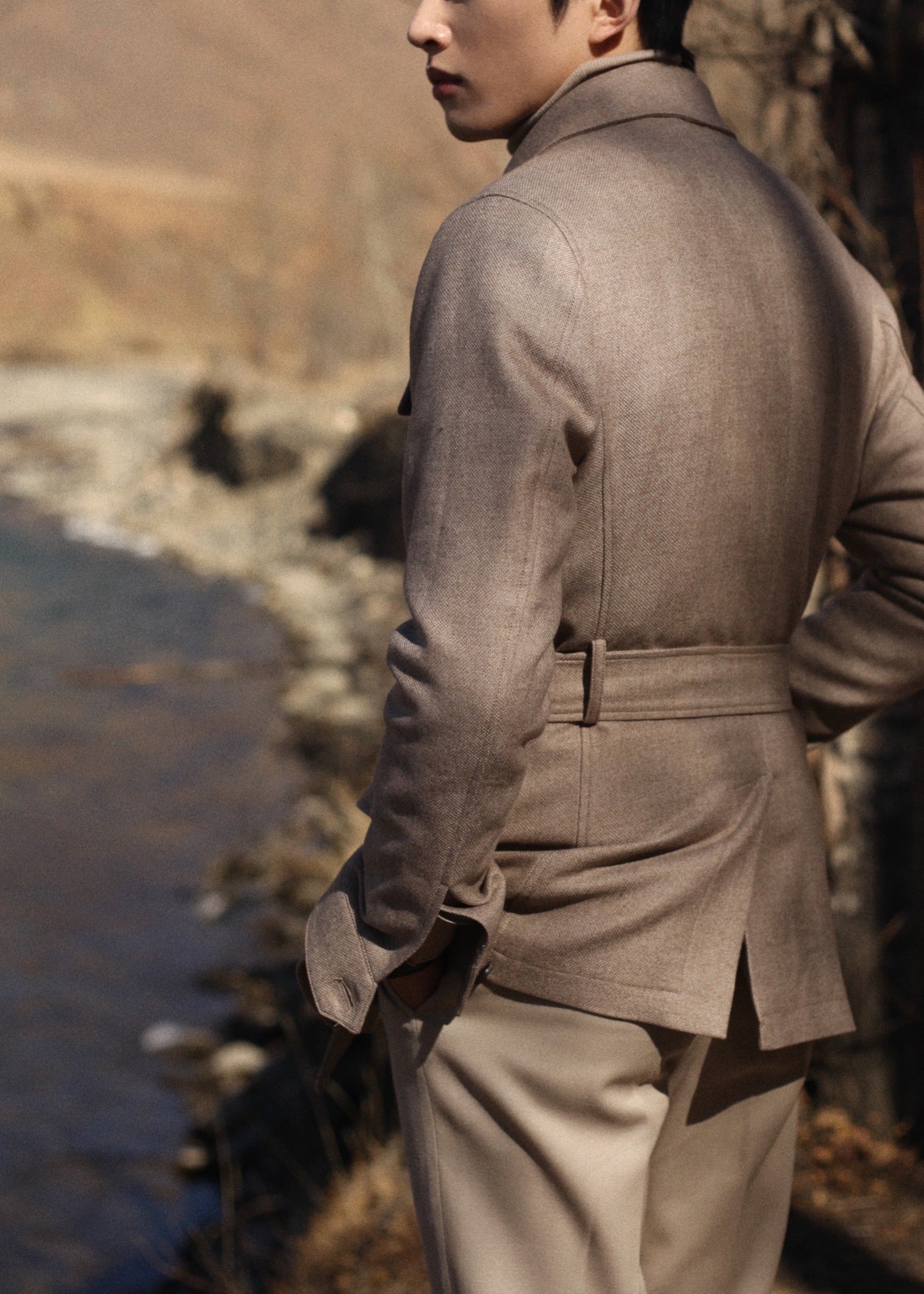 Back view of model wearing Moonland's Altai safari jacket for men, with belted waist and center back vent