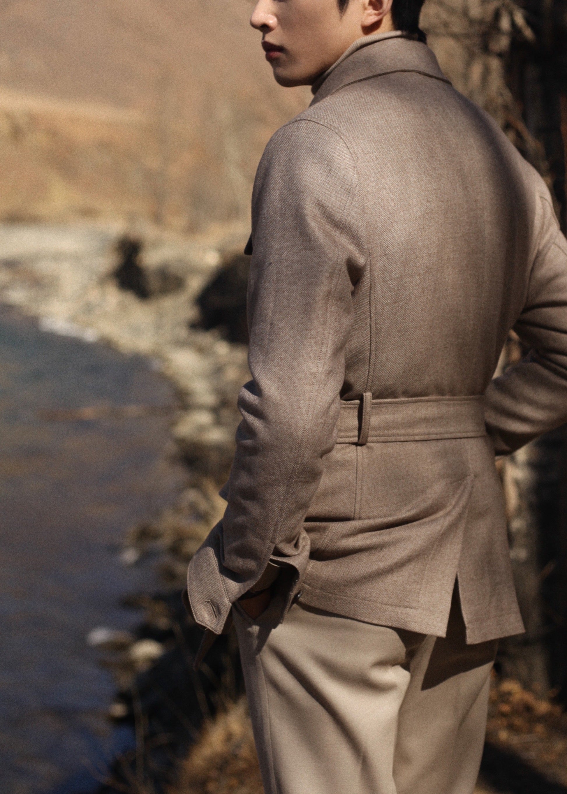 Back view of model wearing Moonland's Altai safari jacket for men, with belted waist and center back vent