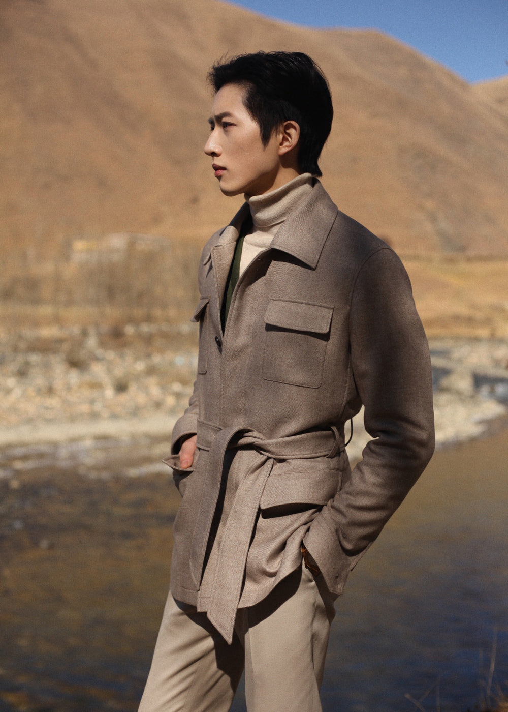Side-front view of model in Moonland's Altai safari jacket for men, showing belted waist and simplified flap pockets