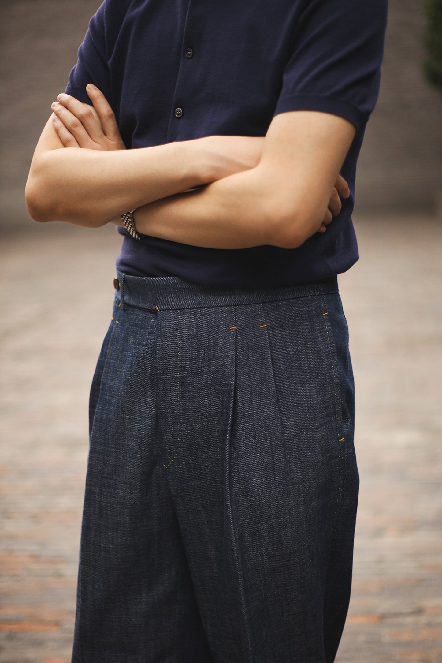 Model wearing Moonland Okayama Denim Trousers, front view with high-rise waist, double pleats, and tailored cut.