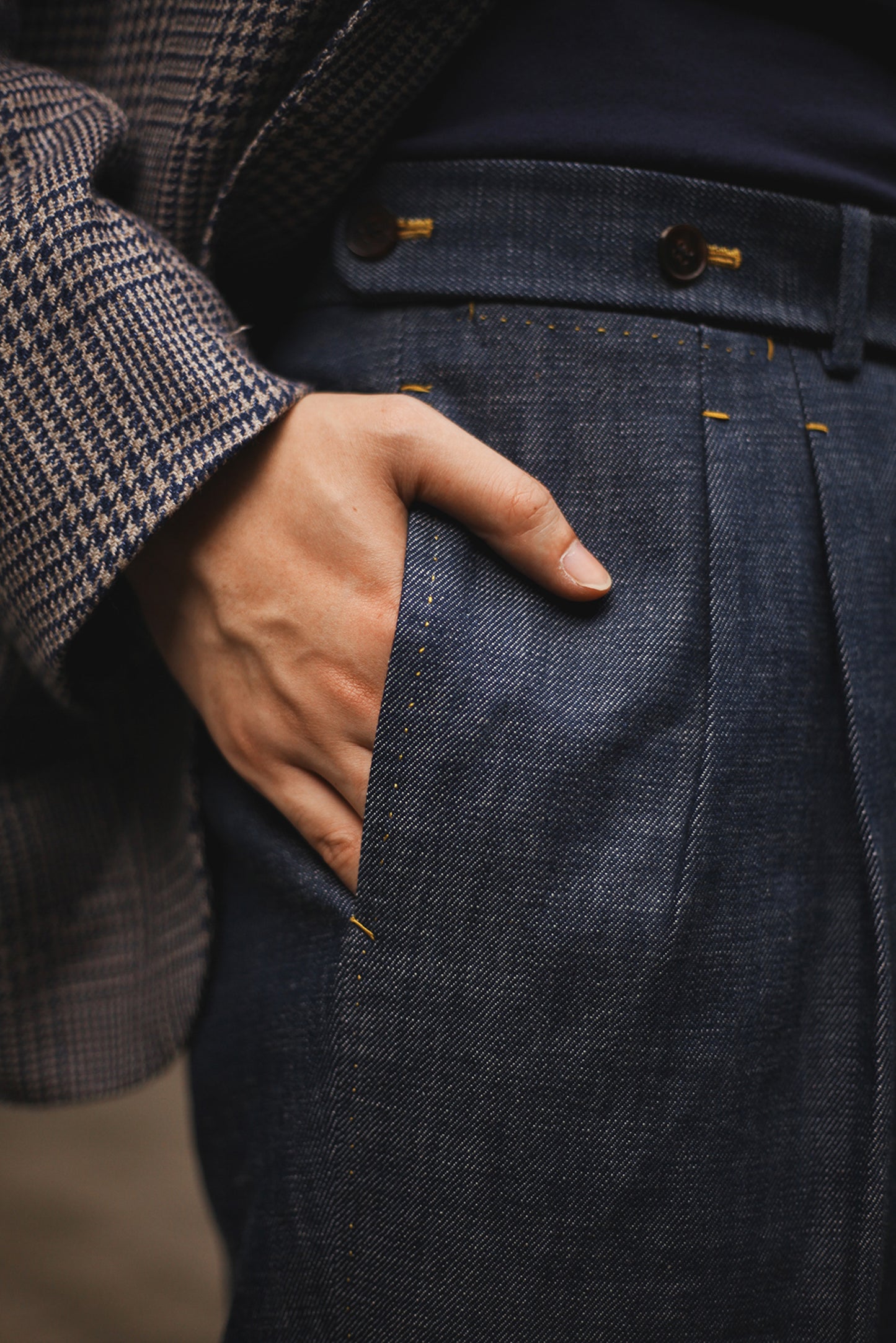 Close-up of model’s hand in side pocket of Moonland Okayama Denim Trousers, showing pleats and waistband details, and hand-finished edges.