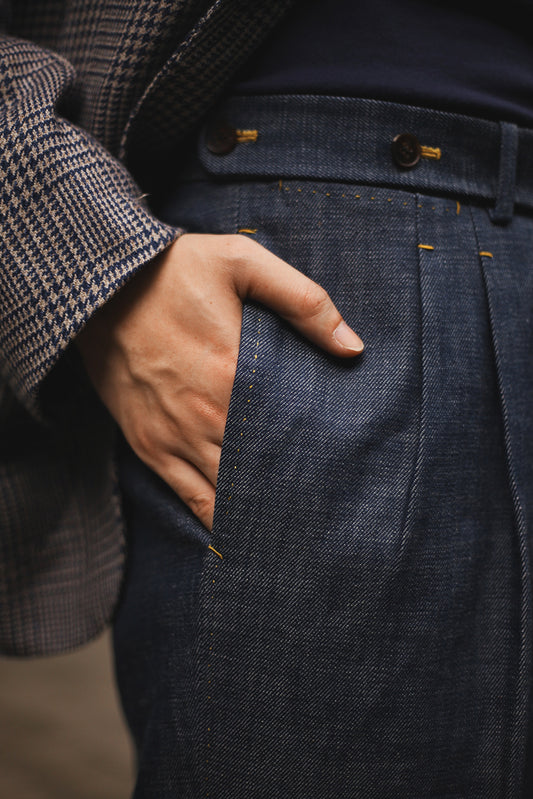 Close-up of model’s hand in side pocket of Moonland Okayama Denim Trousers, showing pleats and waistband details, and hand-finished edges.