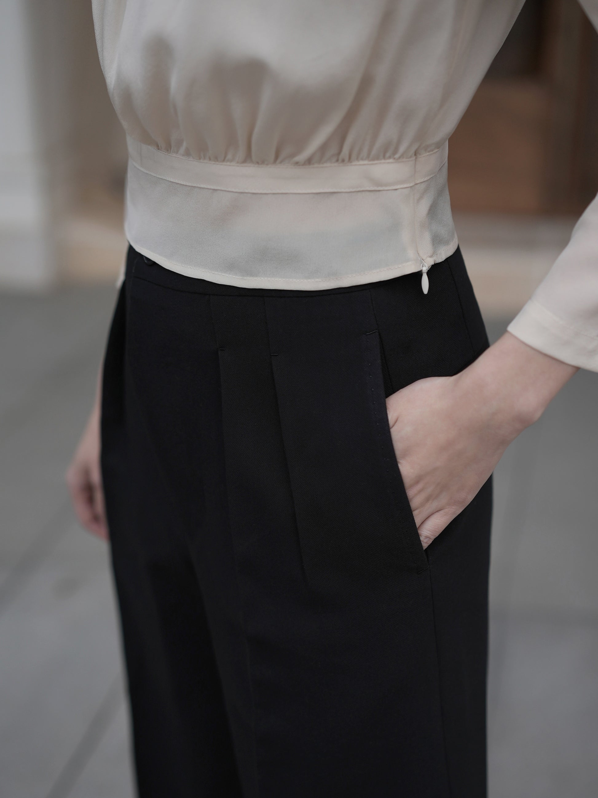 Moonland Monday worsted wool trousers in black, detail focus on the side slant pocket, high-rise waist, straight cut with central pleat turning into a sharp crease.