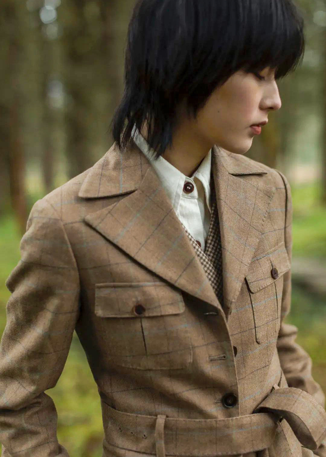 Moonland brown windowpane wool safari jacket front view details, pattern matching, Ulster notch lapel, utility pockets with inverted pleats and defined waist with buckled belt.