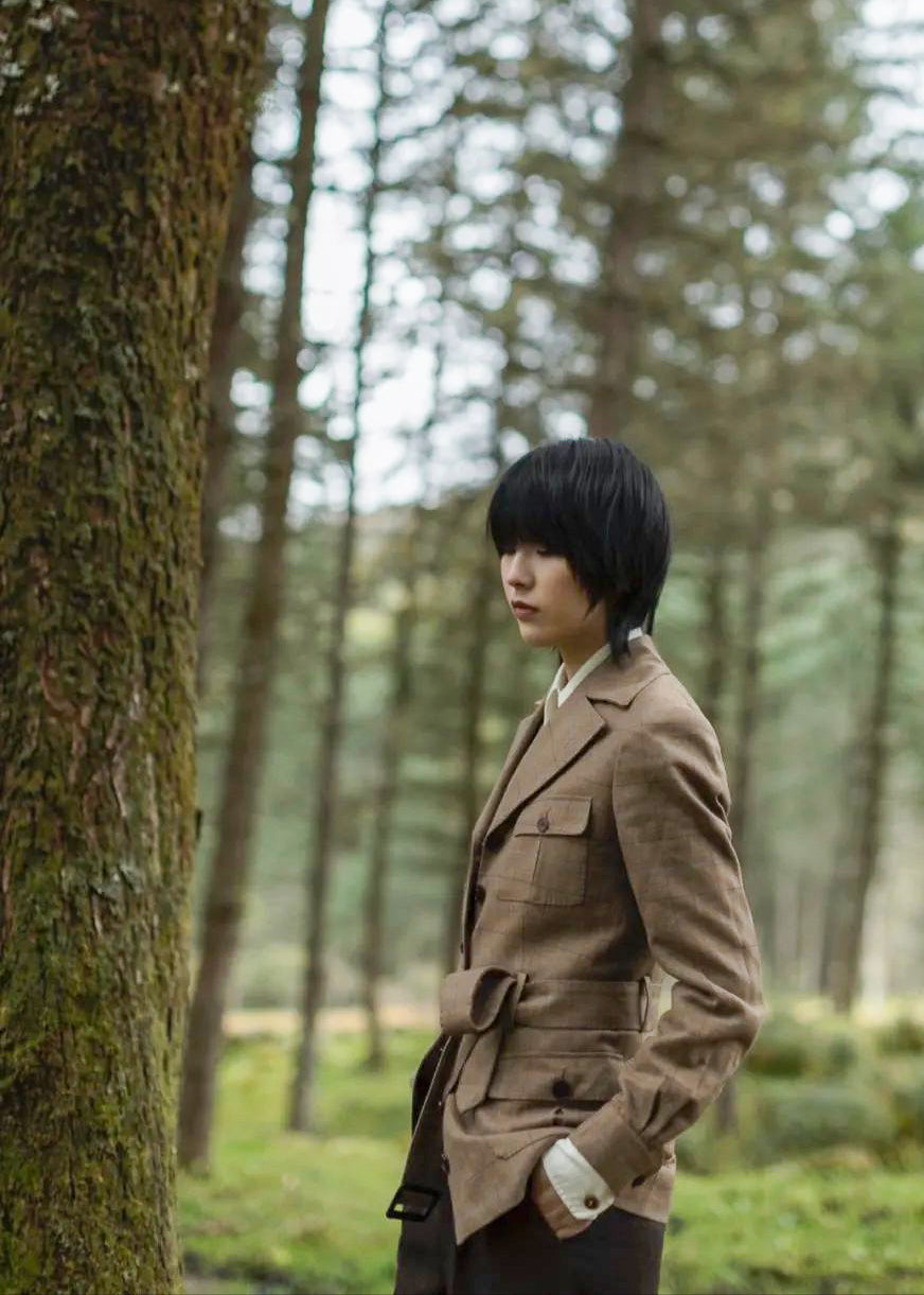 Moonland brown windowpane wool safari jacket side view, Ulster notch lapel, utility pockets with inverted pleats and defined waist with buckled belt.