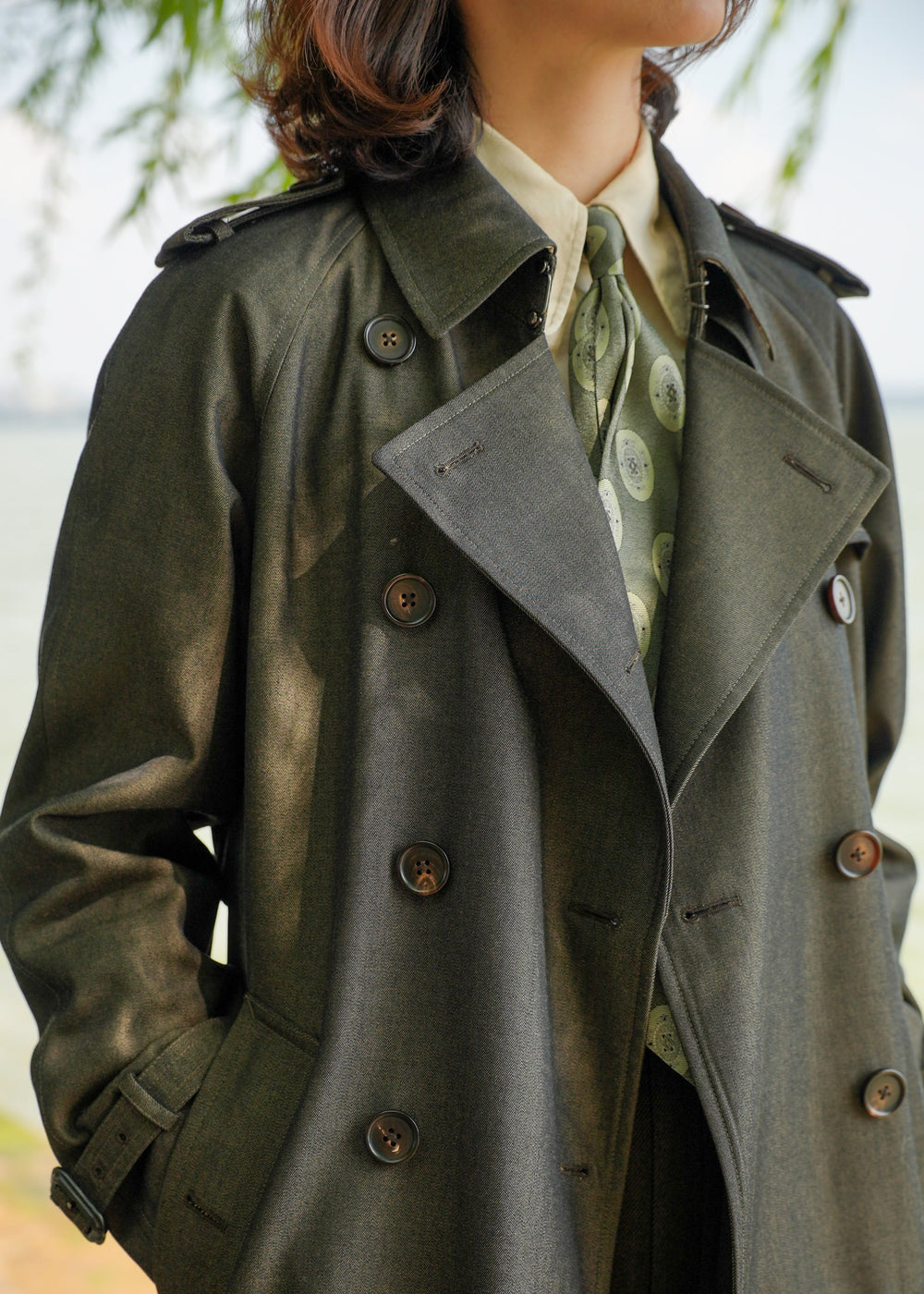 Moonland dark green trench coat with detachable down layer, close chest view, double breasted with epaulettes and sleeve straps, refined buttons and stitching #color_cypress-green
